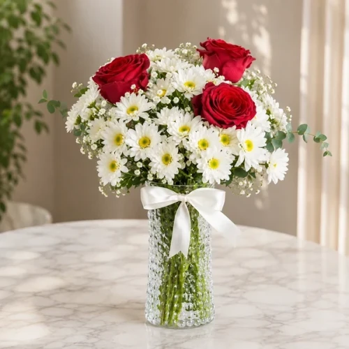 3 rote Rosen und Gänseblümchen in einer Glasvase
